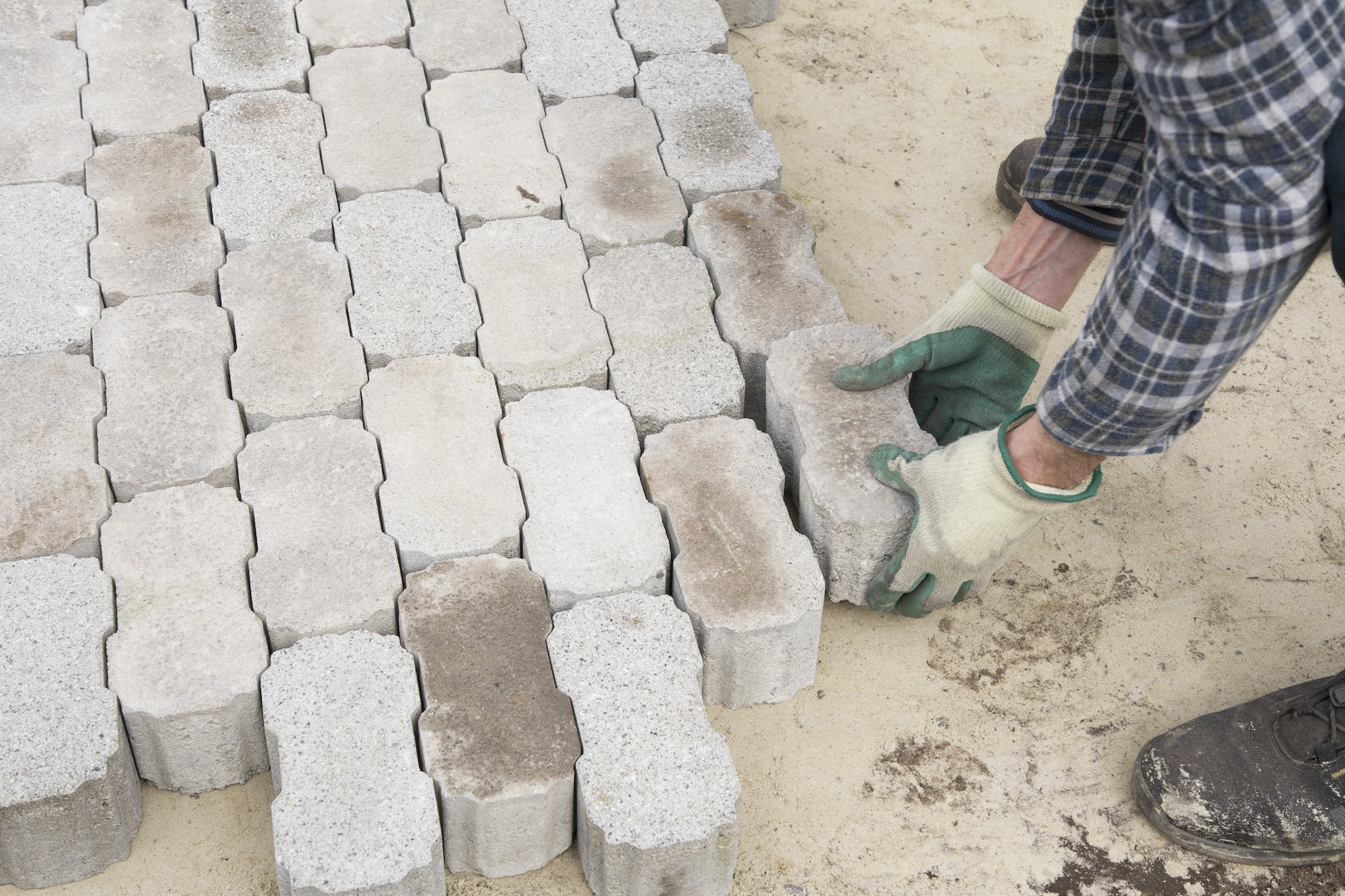 male worker puts brick blocks in the garden path